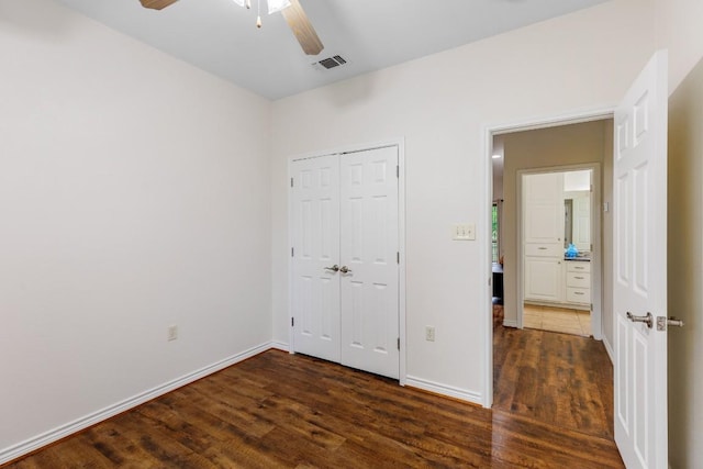 unfurnished bedroom with ceiling fan, a closet, and dark wood-type flooring