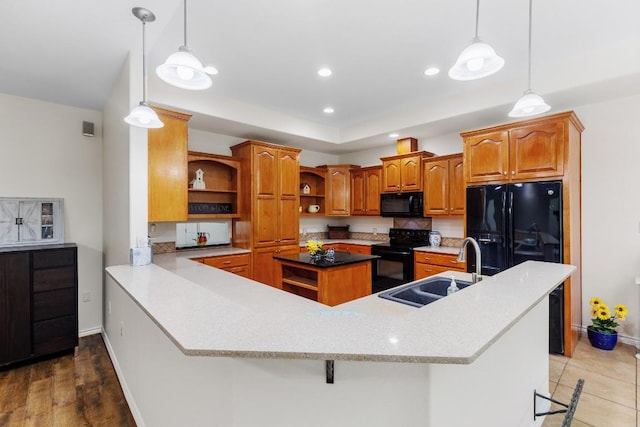 kitchen with black appliances, sink, hanging light fixtures, kitchen peninsula, and a breakfast bar area