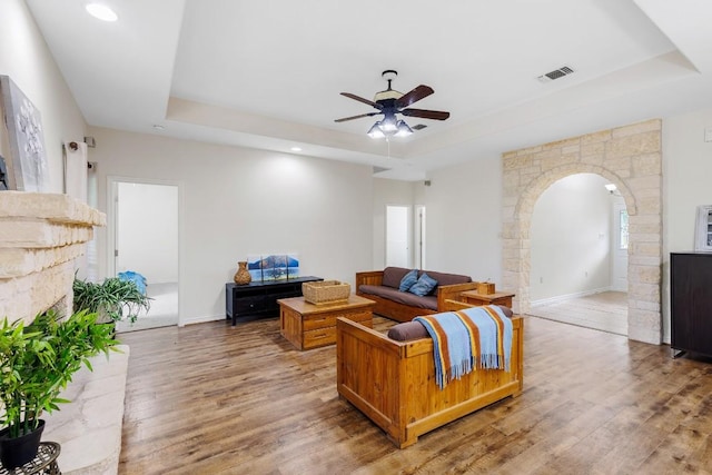 living room featuring a raised ceiling, ceiling fan, and hardwood / wood-style flooring