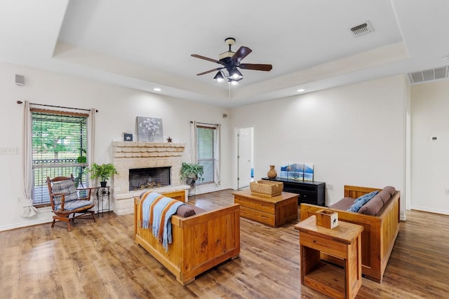 living room with hardwood / wood-style floors, ceiling fan, and a raised ceiling