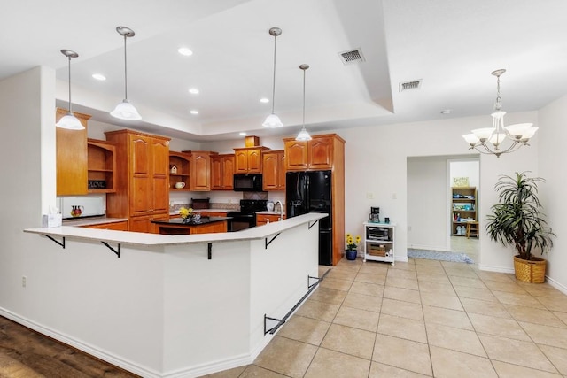 kitchen with a kitchen bar, kitchen peninsula, black appliances, pendant lighting, and an inviting chandelier