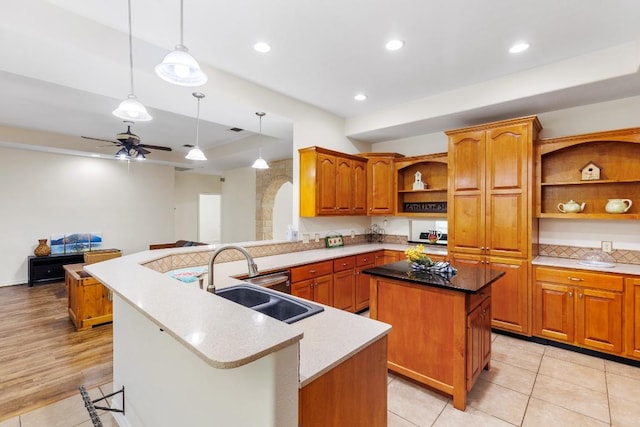 kitchen with kitchen peninsula, sink, hanging light fixtures, and a center island with sink