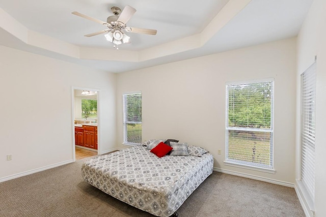 carpeted bedroom with ceiling fan, connected bathroom, and multiple windows