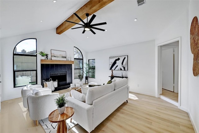 living room featuring light wood-type flooring, lofted ceiling with beams, ceiling fan, and a tiled fireplace