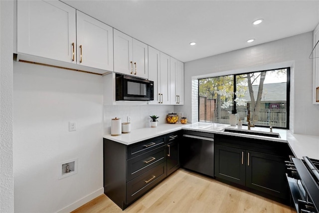 kitchen with sink, light hardwood / wood-style flooring, stainless steel dishwasher, decorative backsplash, and white cabinets