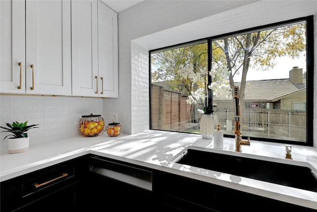 kitchen with a healthy amount of sunlight, white cabinetry, and backsplash