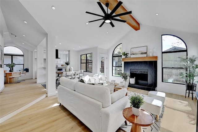 living room with light hardwood / wood-style flooring, beamed ceiling, a healthy amount of sunlight, and a brick fireplace