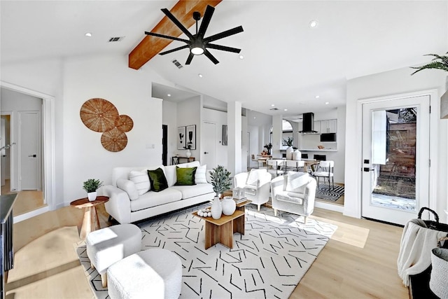 living room with vaulted ceiling with beams, ceiling fan, and light wood-type flooring