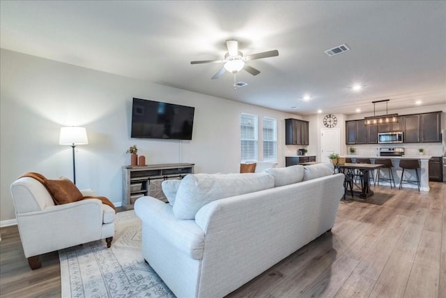 living room featuring light hardwood / wood-style flooring and ceiling fan