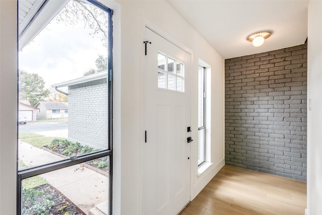 entrance foyer featuring light hardwood / wood-style flooring and brick wall