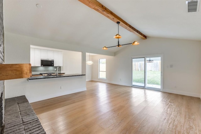 unfurnished living room featuring vaulted ceiling with beams, sink, and light hardwood / wood-style floors