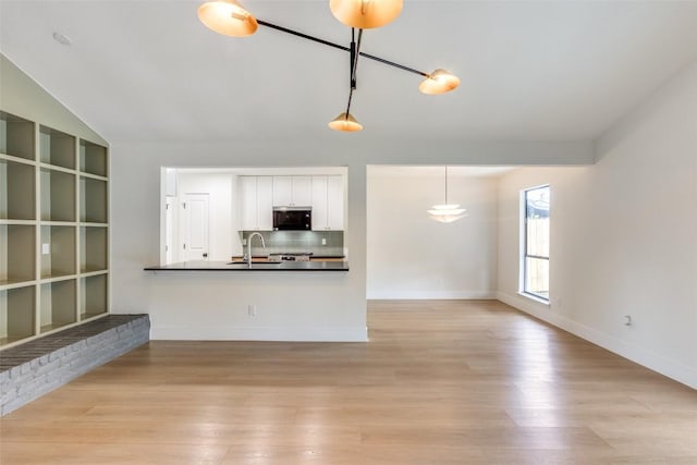 unfurnished living room featuring sink, light hardwood / wood-style floors, and lofted ceiling