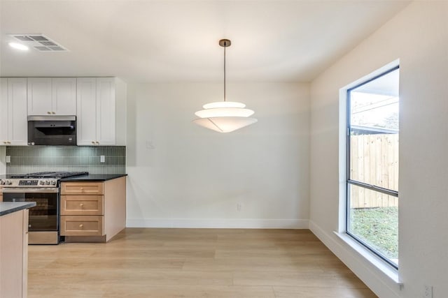 kitchen with plenty of natural light, white cabinetry, stainless steel appliances, and decorative light fixtures