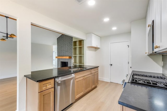 kitchen featuring dishwasher, sink, a brick fireplace, light brown cabinetry, and light wood-type flooring