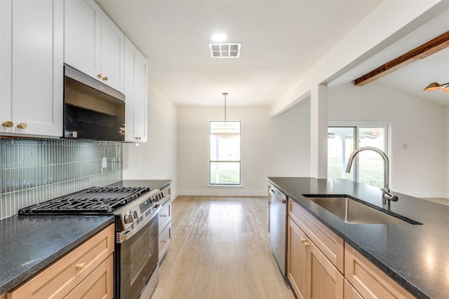 kitchen featuring sink, stainless steel appliances, vaulted ceiling with beams, light hardwood / wood-style floors, and white cabinets