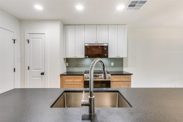 kitchen with decorative backsplash, white cabinetry, sink, and appliances with stainless steel finishes