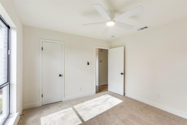 unfurnished bedroom featuring multiple windows, ceiling fan, a closet, and light colored carpet