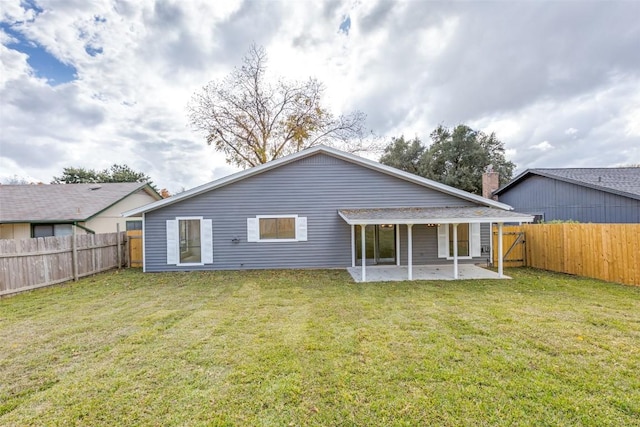 rear view of house with a patio and a lawn