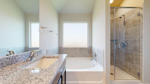 bathroom featuring vanity, vaulted ceiling, and independent shower and bath