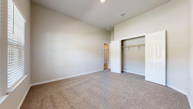 unfurnished bedroom featuring carpet, vaulted ceiling, and a closet