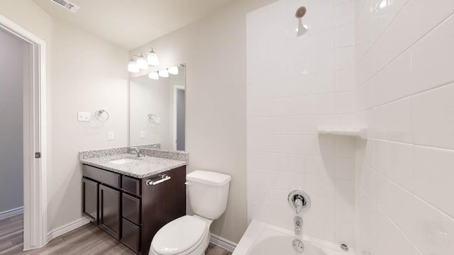 full bathroom featuring vanity, tiled shower / bath combo, hardwood / wood-style flooring, and toilet