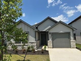 223 Spirit St, Elgin, TX 78621 - ranch-style home featuring an attached garage, driveway, stone siding, and a front yard