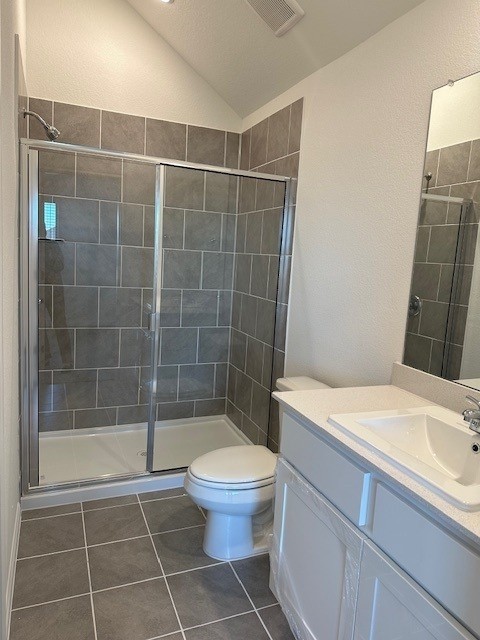 223 Spirit St, Elgin, TX 78621 - bathroom featuring vanity, a shower stall, vaulted ceiling, a textured wall, and tile patterned floors