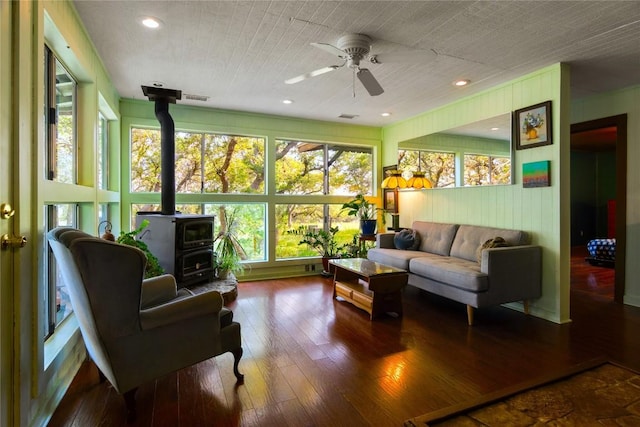 sunroom / solarium featuring ceiling fan and a wood stove