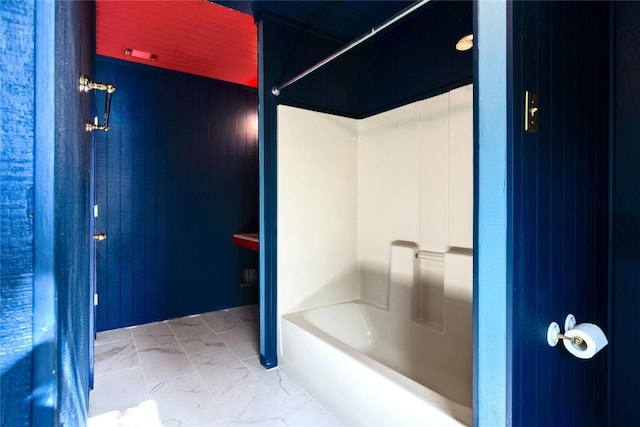 bathroom featuring bathtub / shower combination and wood walls