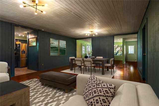 living room with a chandelier, wood-type flooring, wood walls, and wooden ceiling