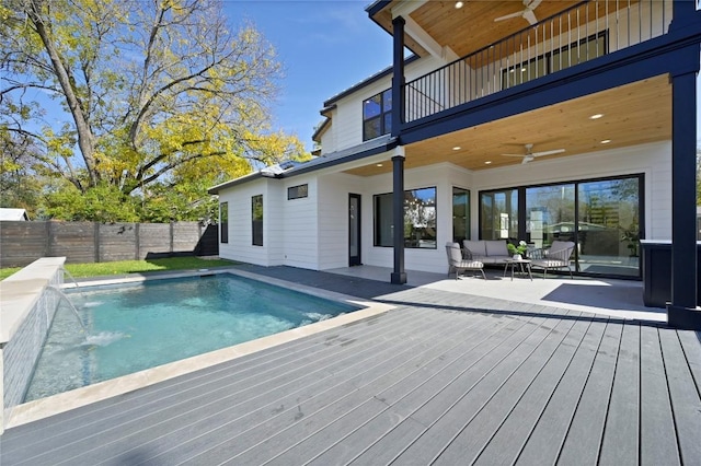 view of swimming pool with outdoor lounge area, pool water feature, ceiling fan, and a wooden deck