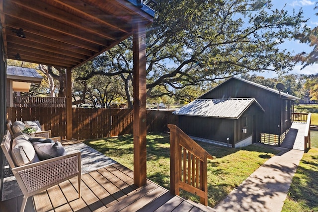 wooden terrace featuring an outbuilding, outdoor lounge area, and a yard