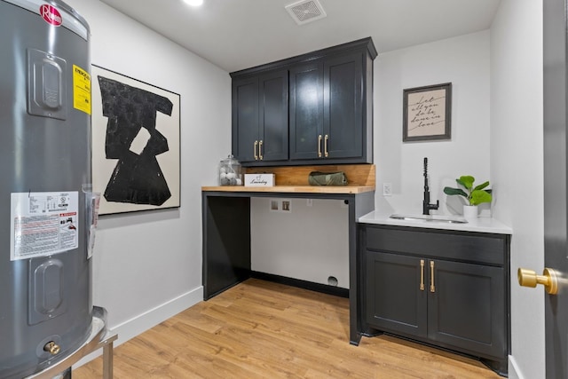 306 Bluebird Cir, Marble Falls, TX 78654 - laundry area featuring water heater, cabinet space, and light wood-type flooring