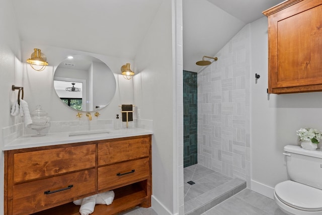 bathroom with tile patterned floors, vanity, vaulted ceiling, tiled shower, and toilet