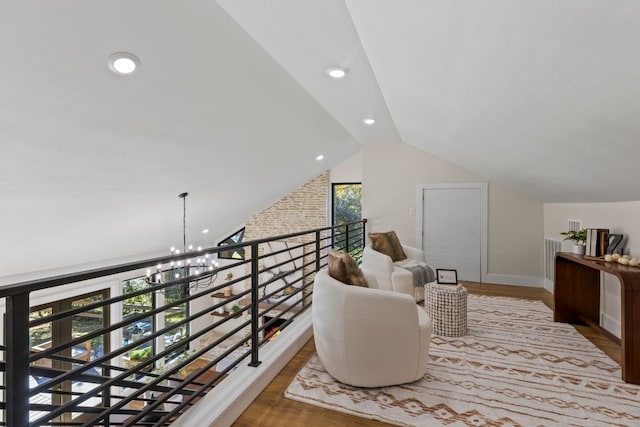 living area featuring hardwood / wood-style floors, a chandelier, and lofted ceiling