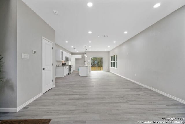 unfurnished living room featuring light wood-type flooring and sink