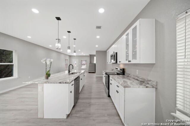 kitchen with white cabinetry, sink, stainless steel appliances, and decorative light fixtures