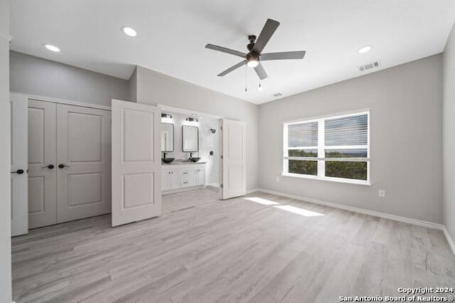 unfurnished bedroom featuring ceiling fan, a closet, ensuite bathroom, and light hardwood / wood-style flooring