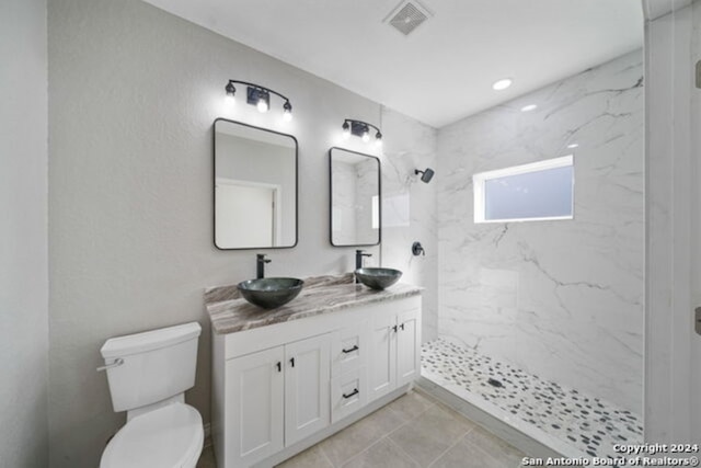 bathroom featuring tiled shower, tile patterned floors, vanity, and toilet