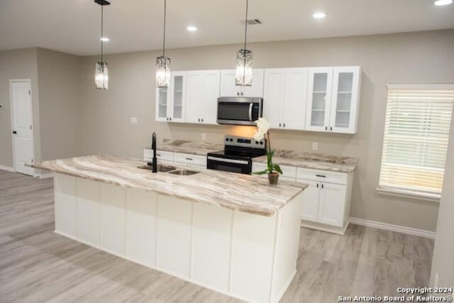 kitchen with stainless steel appliances, sink, light hardwood / wood-style flooring, white cabinetry, and an island with sink