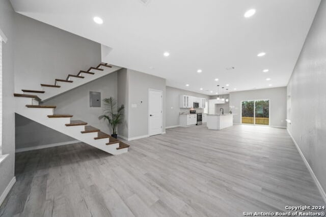 unfurnished living room with light hardwood / wood-style flooring and sink