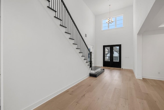 foyer featuring a notable chandelier, light hardwood / wood-style flooring, french doors, and a high ceiling