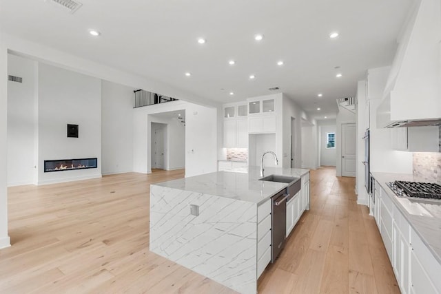 kitchen with appliances with stainless steel finishes, sink, backsplash, white cabinets, and light stone counters