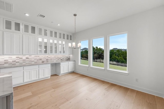 unfurnished dining area featuring light wood-type flooring and an inviting chandelier