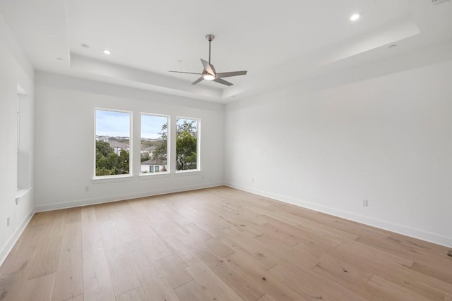 empty room featuring ceiling fan, a raised ceiling, and light hardwood / wood-style floors