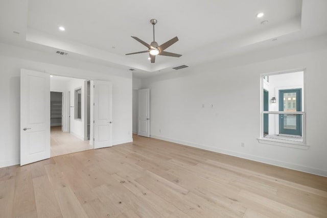 unfurnished bedroom with a raised ceiling, light wood-type flooring, and ceiling fan