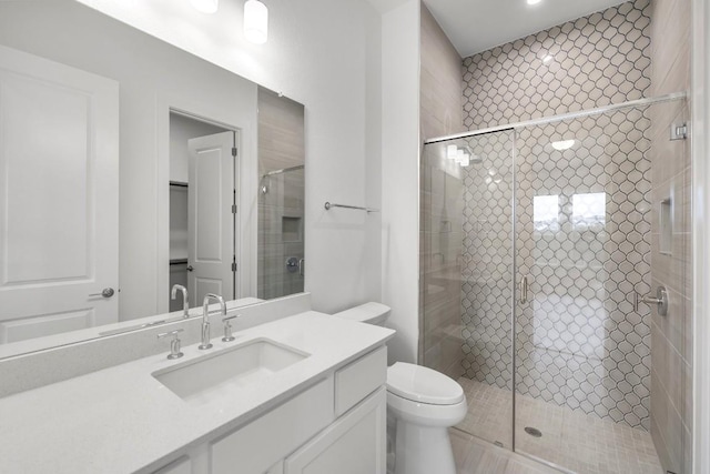 bathroom featuring vanity, a shower with shower door, and toilet