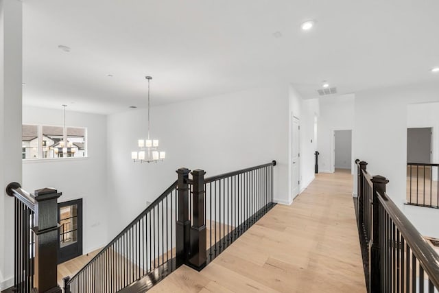 hallway featuring a notable chandelier and light hardwood / wood-style floors