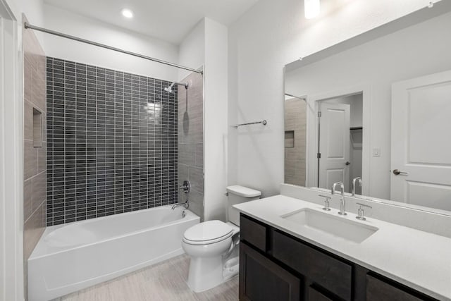 full bathroom featuring vanity, tiled shower / bath combo, and toilet