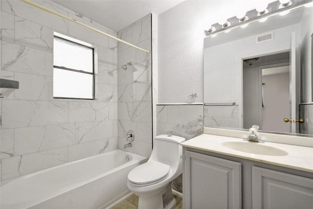 full bathroom with tile patterned floors, vanity, tiled shower / bath combo, and toilet